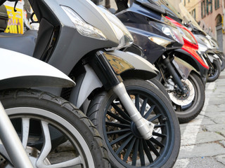 Closeup of motorcycles front wheel parked in the city, in Genoa, Italy.