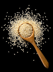white sesame seeds with spoon on black background