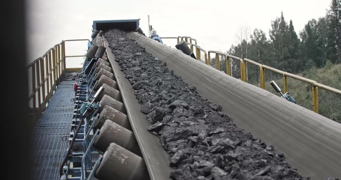 Conveyor belt with coal shooting in slow motion. Close-up there is coal on belt conveyor. Conveyor belt coal. Machine for loading mining in coal obage factory