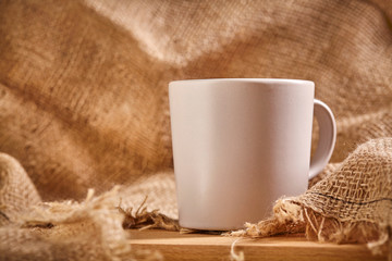 Cup of coffee on wooden board and sackcloth background. Close up.