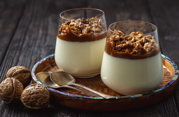 Italian dessert pannacotta in glasses with salted caramel and walnuts. 