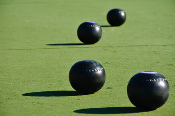 Lawn bowls balls positioned on a smooth playing surface, a bowls green. 
