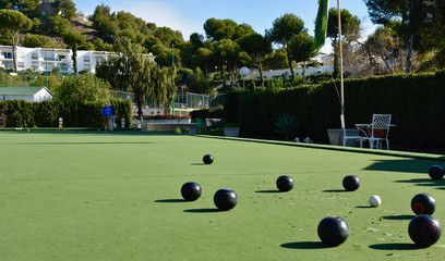 Lawn bowls balls positioned on a smooth playing surface, a bowls green. 