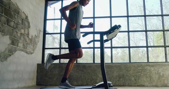 Man running on treadmill in home fitness gym.
