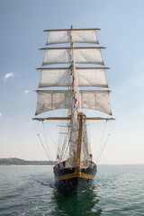 Naklejka na ściany i meble old historical ship (yacht) with white sails, sailing in the sea