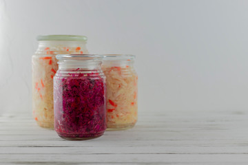 Fototapeta na wymiar three glass jars of fermented white, red cabbage. vegetables on a light background. fermentation is a source of probiotic. copy space