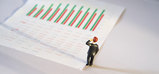 miniature business people and business financial graph data on white paper, business and financial analysis concept