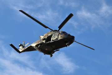 MILITARY HELICOPTER WITH A FOUR-BLADE ROTOR FLYING OVER AN AREA