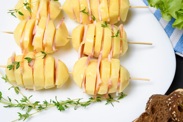 Alternative barbecue: potato pieces with pork bacon on skewer
