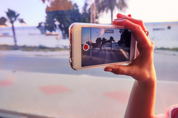 Tourist picks up landscapes from the bus window on a smartphone. Travel by bus. Woman hand holding...