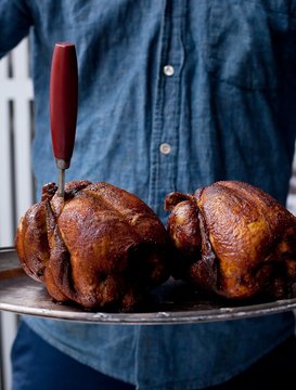 Midsection of man holding roasted chicken