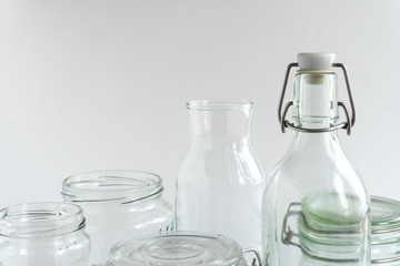 A variety of empty glass jars and bottles at white monochrome background. Zero waste concept.