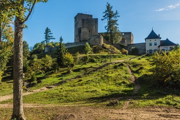 Fototapeta na wymiar Landstejn, Czech Republic - September 29 2019: View of a medieval knights castle made of stone standing on a green hill surrounded with trees. Bright sunny day with blue sky.