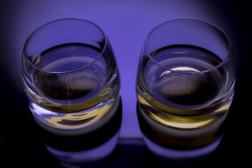 Two glasses whisky black background blue light