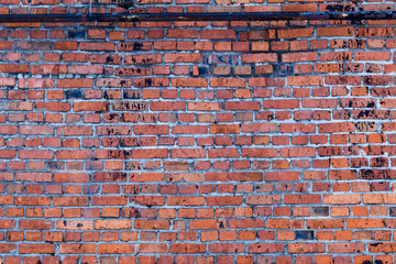 an old red brick wall taken down on a cloudy winter day