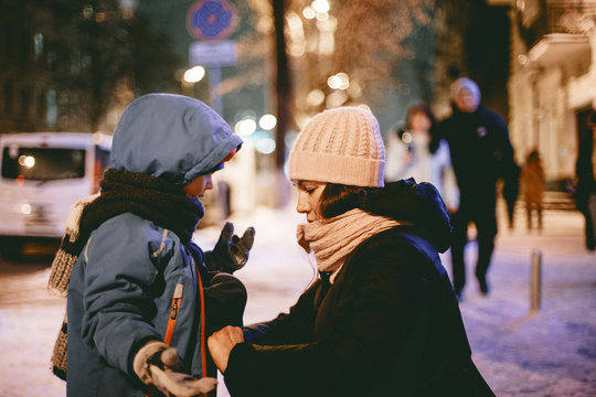 Mother communicating with son while zipping his jacket in street