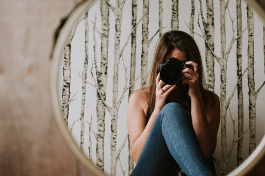 Woman holding camera taking photo of her reflection in the mirror.