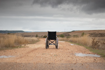Rear vision of a wheelchair isolated in the middle of a path