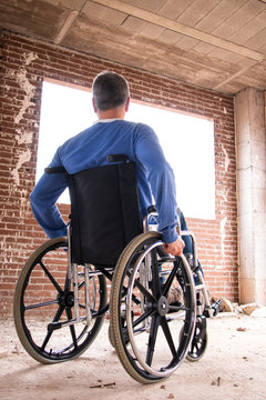 A man in a wheelchair in a house under construction looking outside