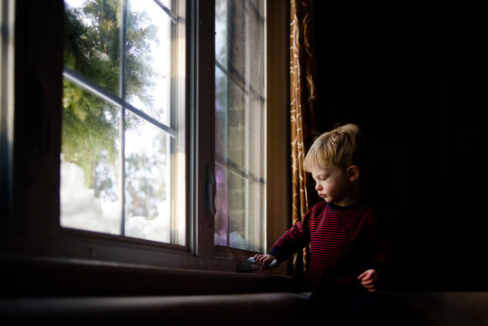A little boy tries to open a window.