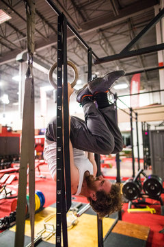 Man holding upside down position during work out with rings in gym