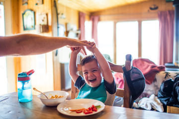 Father reach to tickle his son while at the table