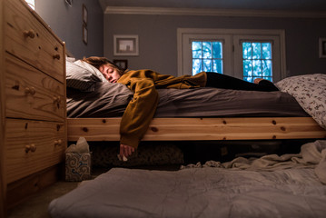 disheveled young woman laying in bed holding tissue and tissue box