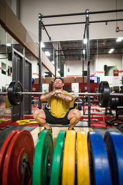 muscular man completes squats at the gym