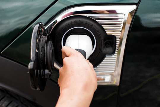 hand plugging in an electric car