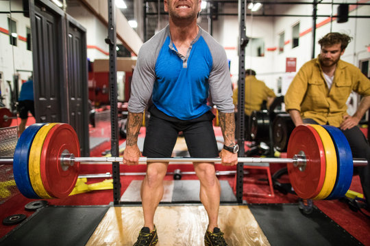 mid section of man preforming deadlift at the gym