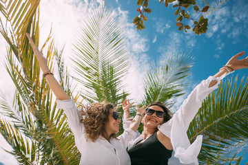A pair of girls in love rejoice, hugging at a tropical resort.