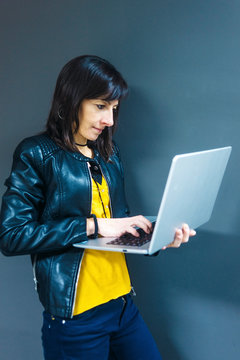 Fashion business woman working on laptop while standing against