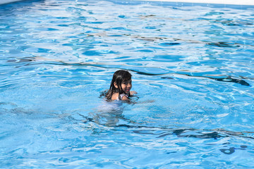 Pretty girl smiling and swimming in the outdoor pool