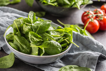 Fresh baby spinach in bowl on dark kitchen table
