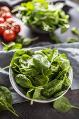 Fresh baby spinach in bowl on dark kitchen table