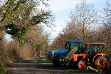 country lane with agricultural tractor and hedgreow with oak tree