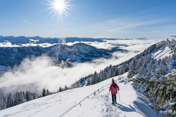 nice senior woman snowshoeing on the Nagelfluh chain above a sea of fog over Bregenz Wald mountains, Hochgrat, Steibis,Bavarian alps, 