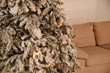 Christmas tree decorated with toys stands near the window in the evening where a garland