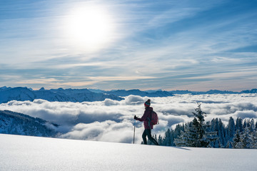 nice senior woman snowshoeing on the Nagelfluh chain above a sea of fog over Bregenz Wald...
