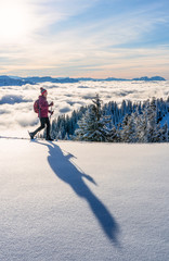 nice senior woman snowshoeing on the Nagelfluh chain above a sea of fog over Bregenz Wald...