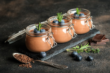 Chocolate mousse in glass jar with berries on a dark background copy space. Homemade dessert.