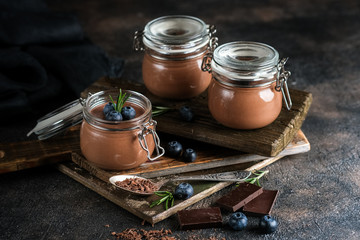 Chocolate mousse in glass jar with berries on a dark background copy space. Homemade dessert.