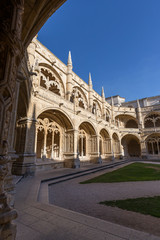Empty inner courtyard and ornamental cloisters at the historic Manueline style Mosteiro dos Jeronimos (Jeronimos Monastery) in Belem, Lisbon, Portugal, on a sunny day.