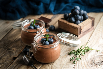 Chocolate mousse in glass jar with berries on a rustic background copy space. Homemade dessert.