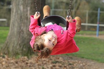 little girl happily swinging at the park