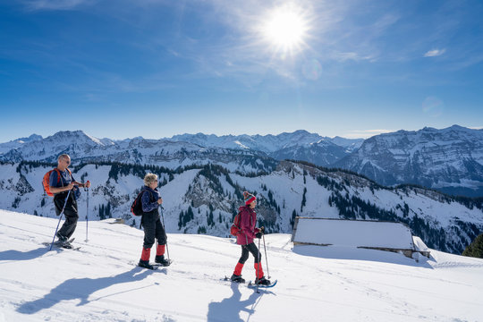 group of 3 senior adults snowshoeing  in the Bregenz wald mountains above the village of Bezau, Vorarlberg, Austria