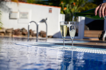 Pool party with two glasses with  bubbles white champagne or cava wine, romantic event or all inclusive holidays