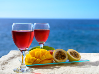 Two glasses with rose wine served outdoor with exotic fruits on tropical island La Palma, Canary islands, Spain with beautiful blue ocean view