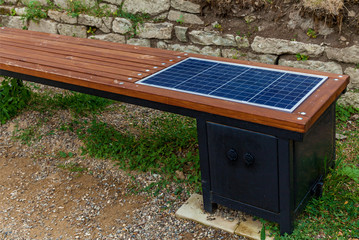 A wooden bench with a solar panel for charging a phone