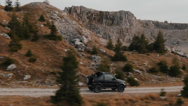 Aerial drone view of an off-road car driving on a mountain road